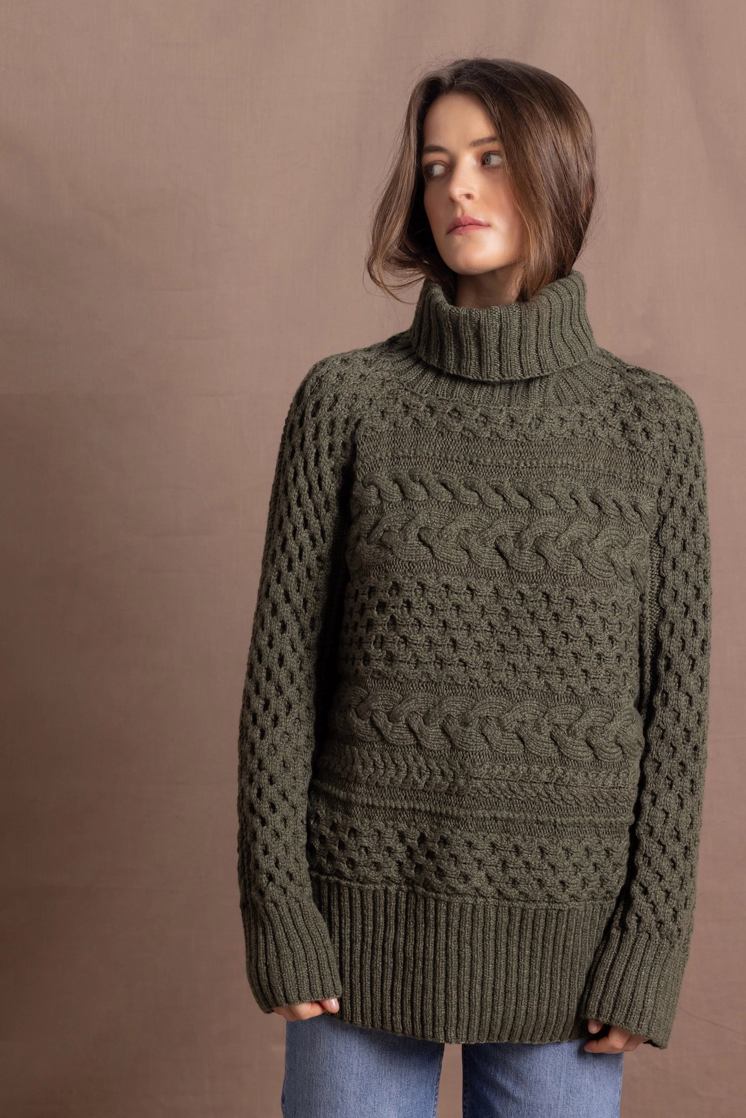 a lady wears a 100% cashmere aran sweater in fern green