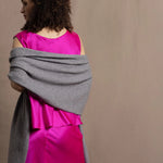 Lady wears large cashmere wrap shawl in Grey against bright pink silk clothing