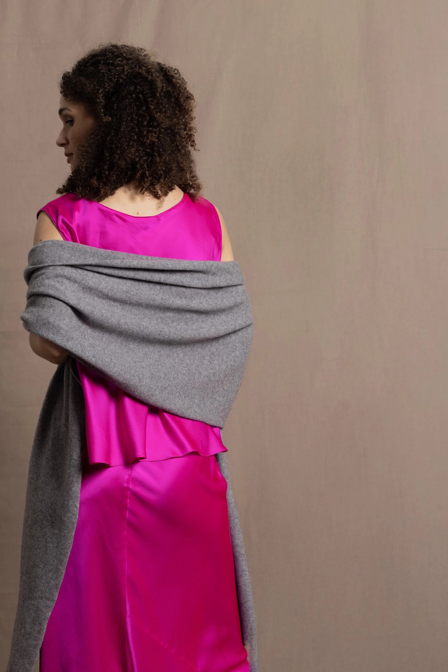 Lady wears large cashmere wrap shawl in Grey against bright pink silk clothing