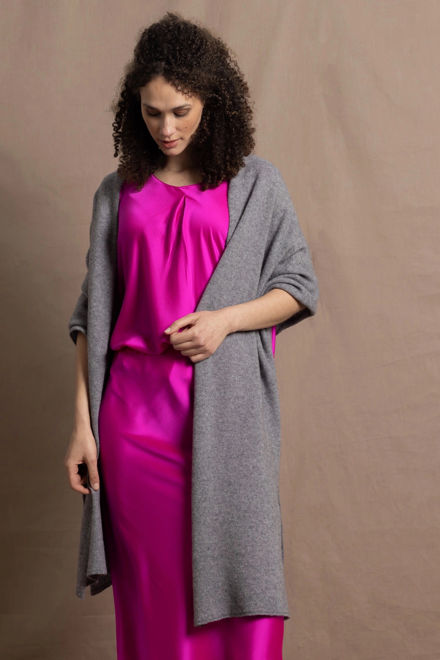 Lady wears large cashmere wrap shawl in Grey against bright pink silk clothing