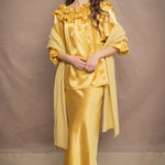 a woman wears a pure 100% cashmere wrap shawl over a silk blouse top and matching silk skirt in pale yellow from Irish brand Madigan