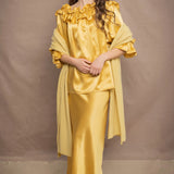a woman wears a pure 100% cashmere wrap shawl over a silk blouse top and matching silk skirt in pale yellow from Irish brand Madigan
