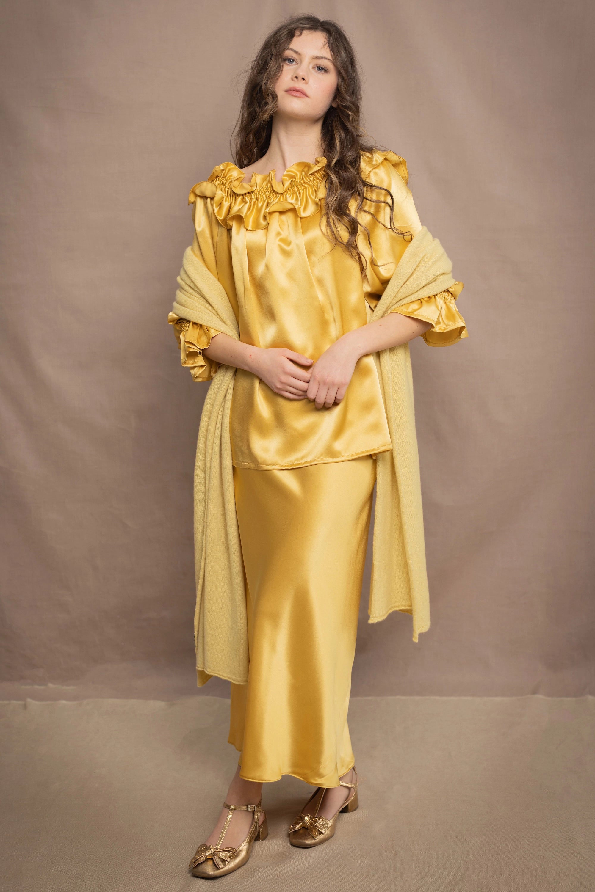 a woman wears a pure 100% cashmere wrap shawl over a silk blouse top and matching silk skirt in pale yellow from Irish brand Madigan
