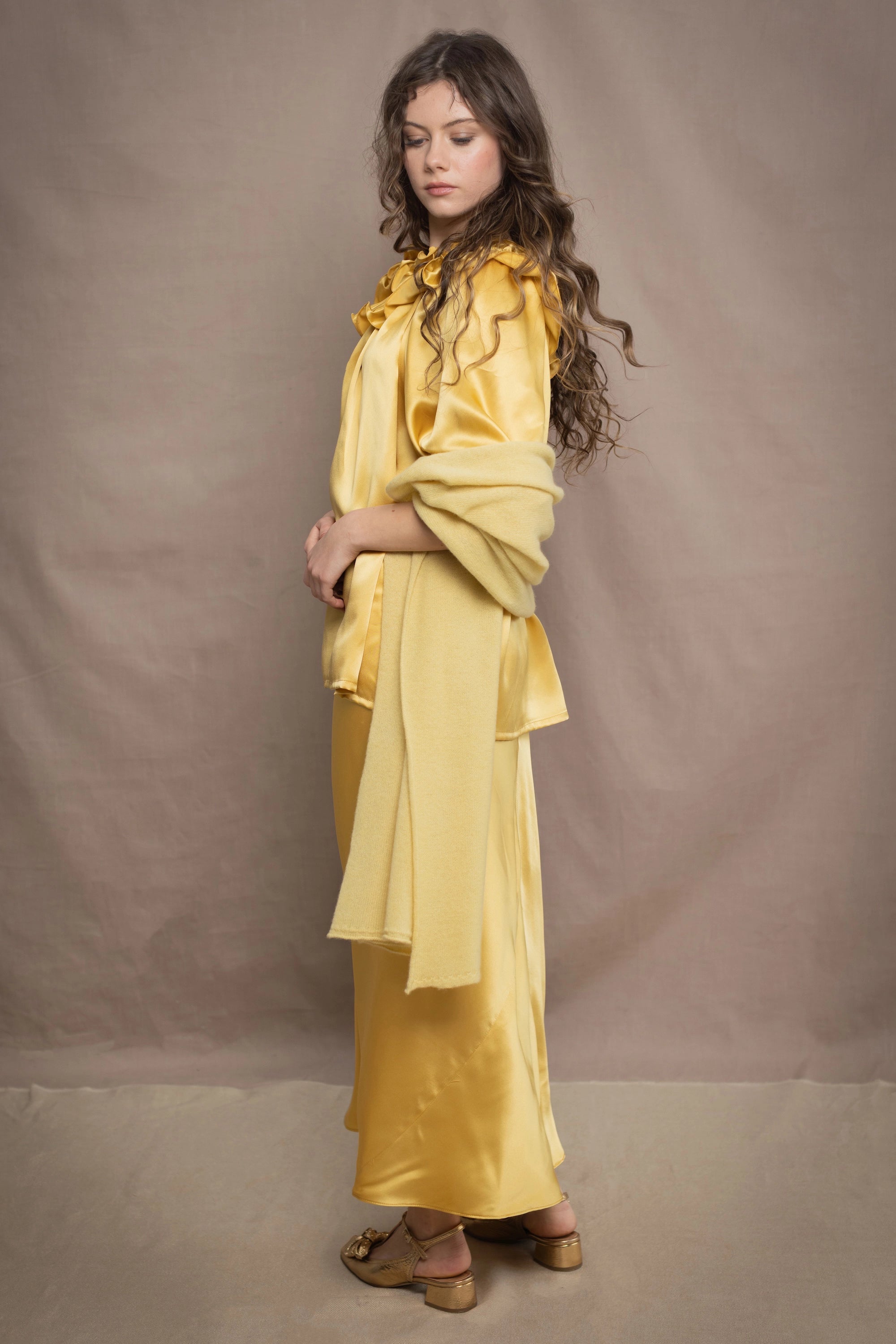 a woman wears a pure 100% cashmere wrap shawl over a silk blouse top and matching silk skirt in pale yellow from Irish brand Madigan