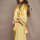 a woman wears a pure 100% cashmere wrap shawl over a silk blouse top and matching silk skirt in pale yellow from Irish brand Madigan