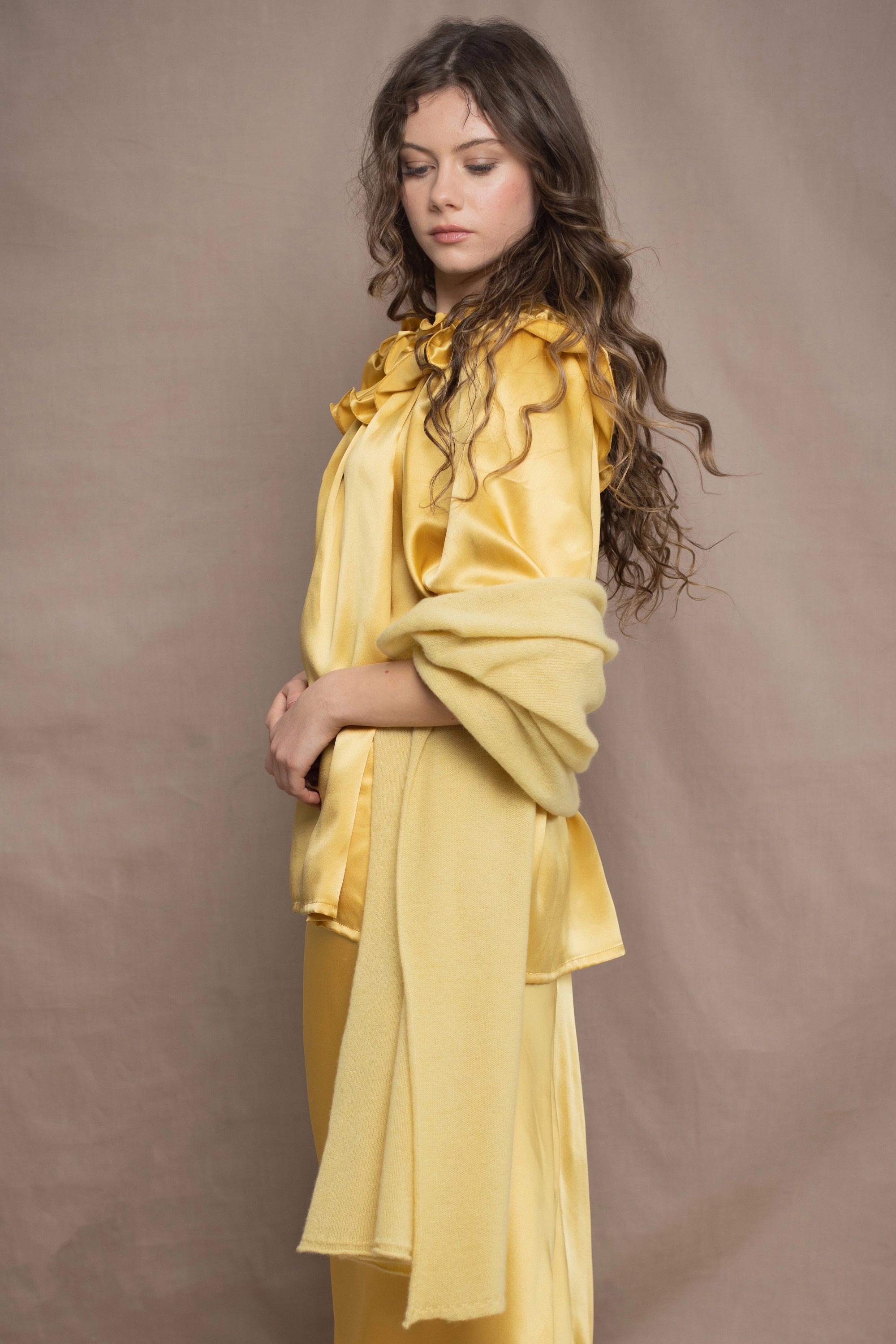 a woman wears a pure 100% cashmere wrap shawl over a silk blouse top and matching silk skirt in pale yellow from Irish brand Madigan