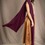 A woman models a deep plum burgundy draped cashmere wrap or shawl over her shoulder