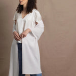 a woman wears a white cashmere wrap shawl over her shoulders with a silk white tee and jeans