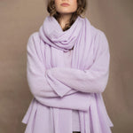 A woman wears a light purple cashmere scarf wrap over a matching cashmere sweater