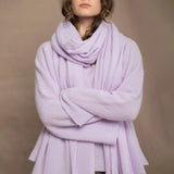 A woman wears a light purple cashmere scarf wrap over a matching cashmere sweater