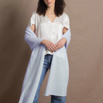 a woman wears a pale blue cashmere wrap shawl over her shoulders with a silk white tee and jeans