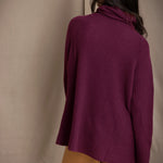 A woman shown from the back wearing a fisherman cashmere knit sweater jumper  in a deep plum purple color by Irish brand Madigan Cashmere