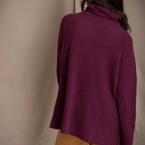 A woman shown from the back wearing a fisherman cashmere knit sweater jumper  in a deep plum purple color by Irish brand Madigan Cashmere