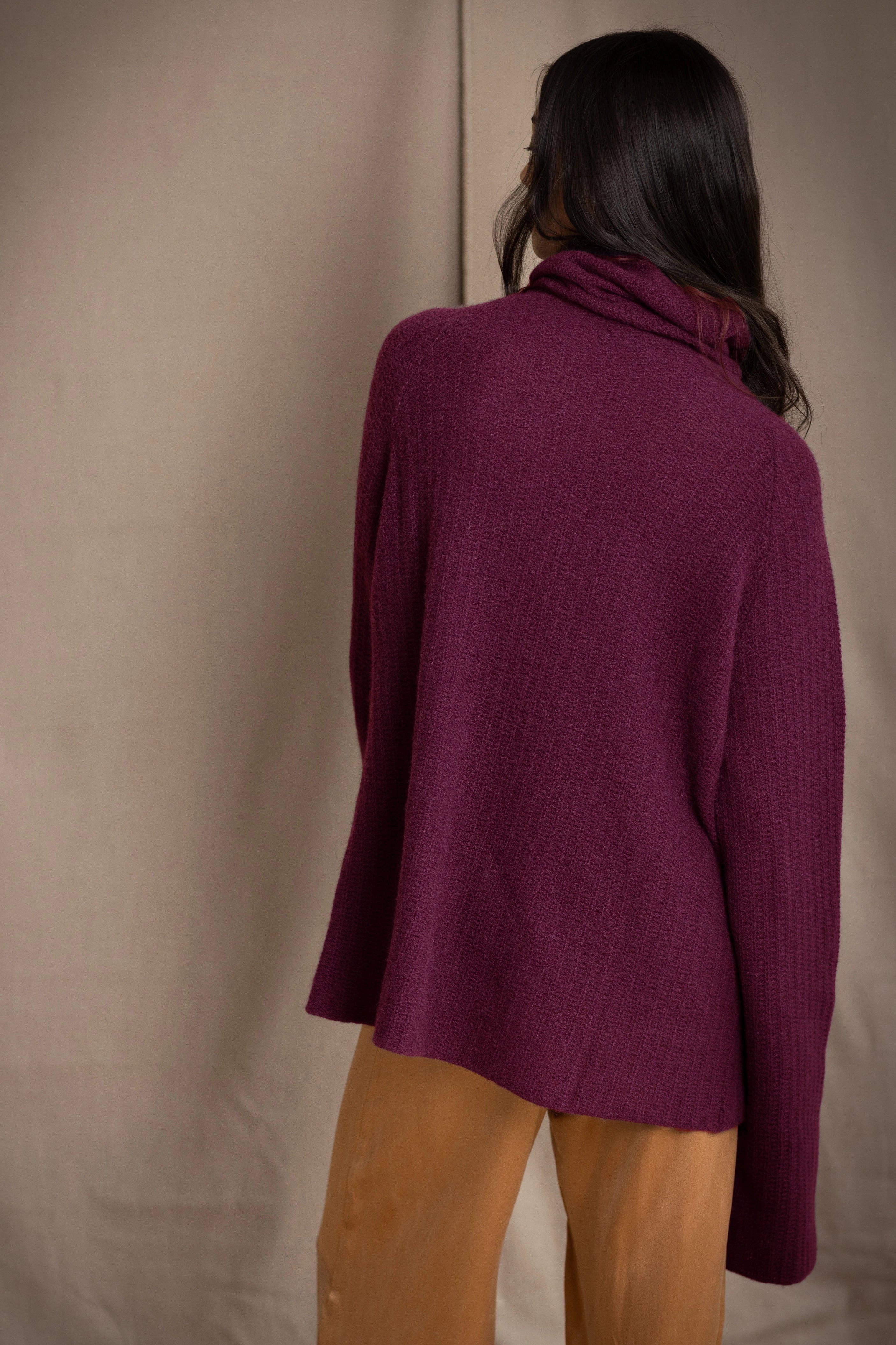 A woman shown from the back wearing a fisherman cashmere knit sweater jumper  in a deep plum purple color by Irish brand Madigan Cashmere