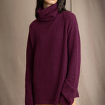 A woman wearing a fisherman cashmere knit sweater jumper  in a deep plum purple color by Irish brand Madigan Cashmere