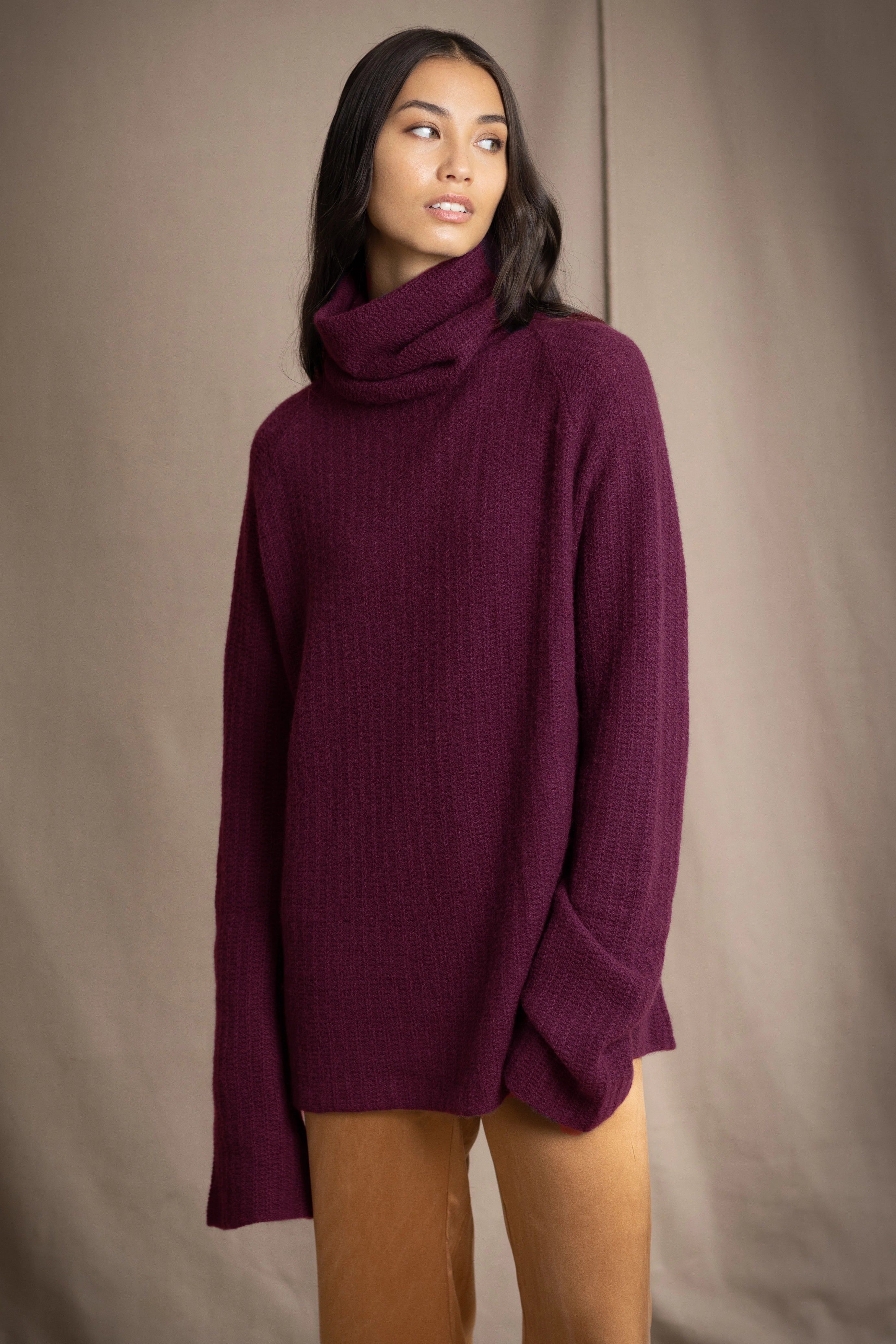A woman wearing a fisherman cashmere knit sweater jumper  in a deep plum purple color by Irish brand Madigan Cashmere