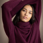 A woman wearing a fisherman cashmere knit sweater jumper  in a deep plum purple color by Irish brand Madigan Cashmere