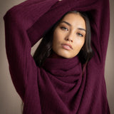 A woman wearing a fisherman cashmere knit sweater jumper  in a deep plum purple color by Irish brand Madigan Cashmere