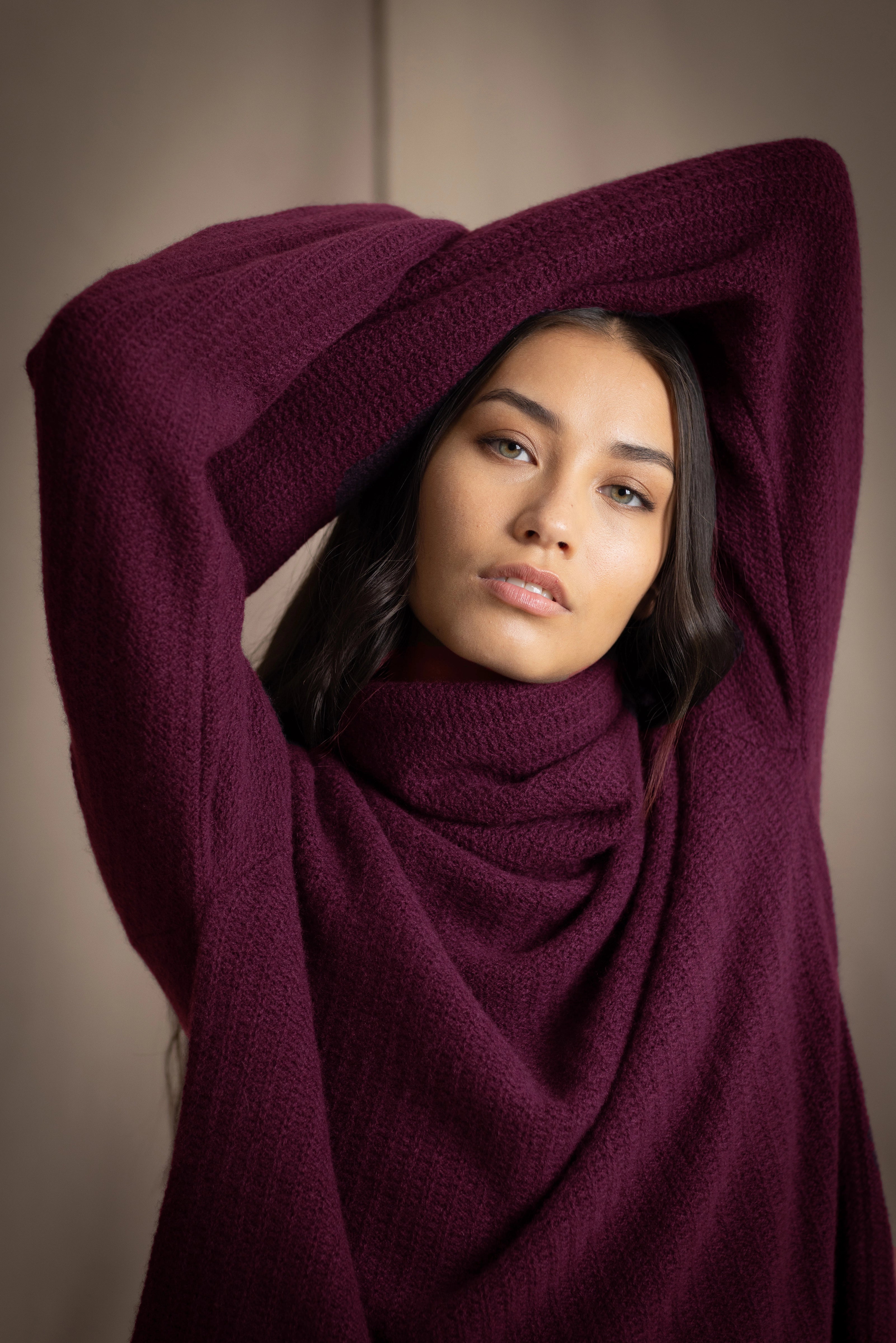 A woman wearing a fisherman cashmere knit sweater jumper  in a deep plum purple color by Irish brand Madigan Cashmere