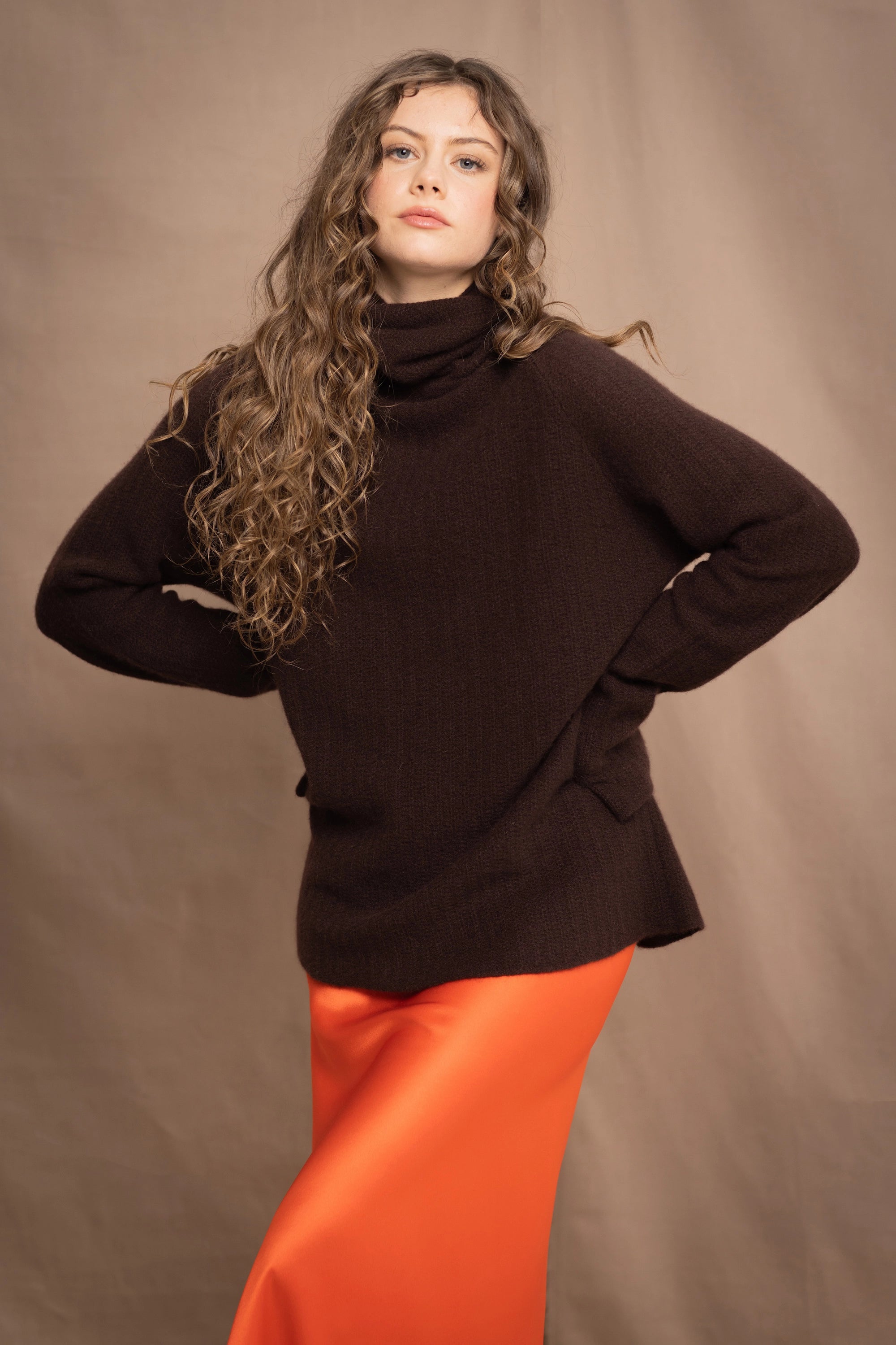 a women wears a pure 100% cashmere turtleneck fisherman sweater in dark brown over a silk skirt in orange by Irish brand Madigan
