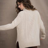 A woman wears a hand knit Irish 100% Cashmere Aran Sweater with Turtleneck in cream beige colour