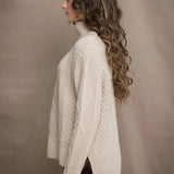 A woman wears a hand knit Irish 100% Cashmere Aran Sweater with Turtleneck in cream beige colour