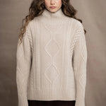 A woman wears a hand knit Irish 100% Cashmere Aran Sweater with Turtleneck in cream beige colour