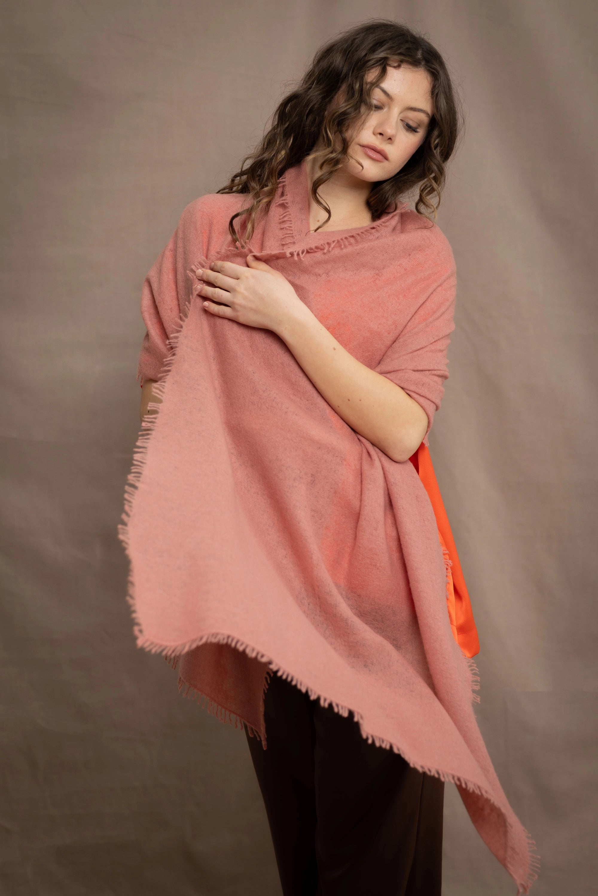 a woman wears a lightweight cashmere shawl cardigan in a dusty pink colour by Irish brand Madigan