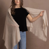 A woman wears a lightweight, fine cashmere shawl over her shoulders with a black cashmere t-shirt underneath