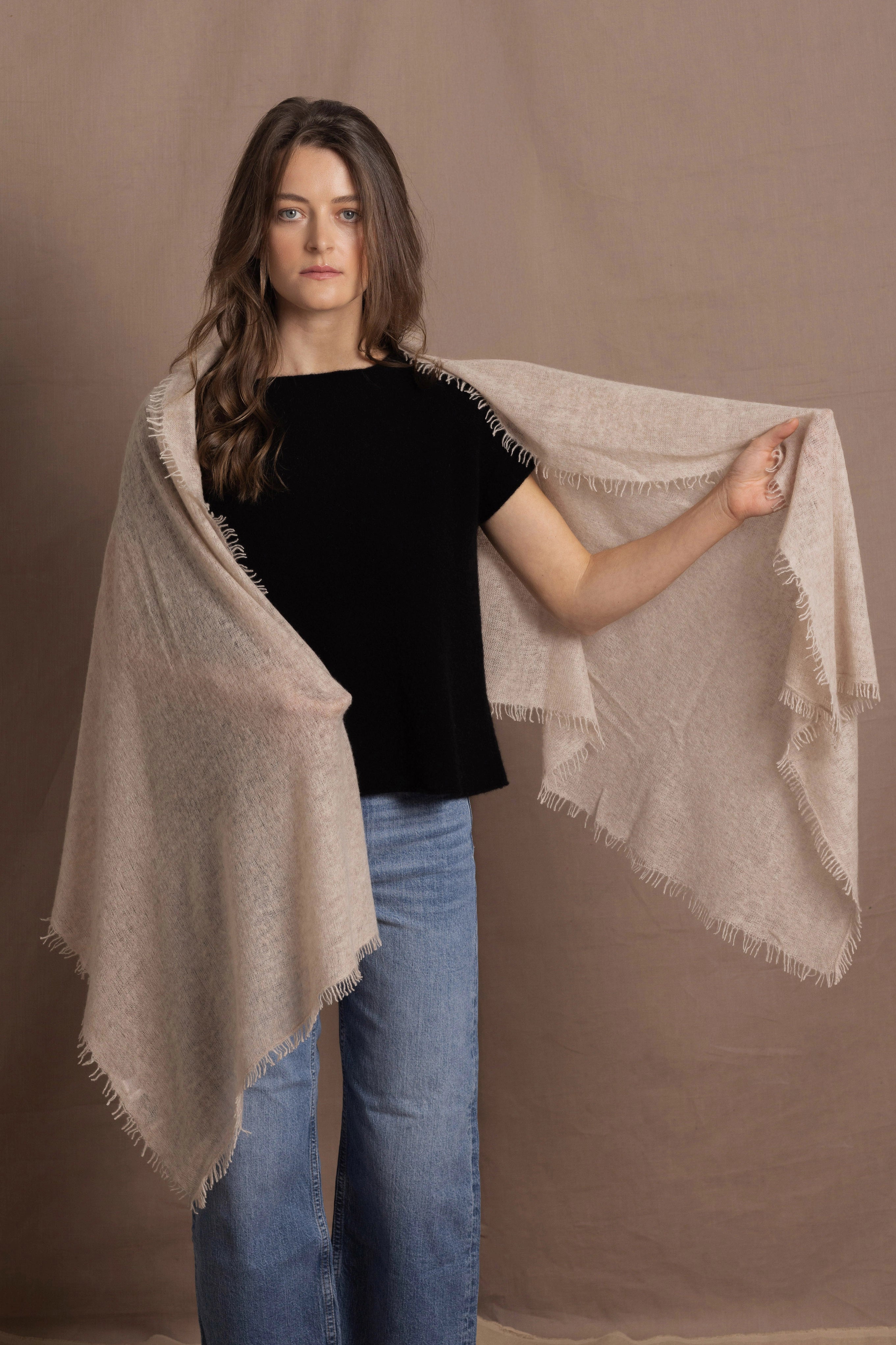 A woman wears a lightweight, fine cashmere shawl over her shoulders with a black cashmere t-shirt underneath
