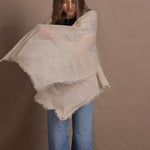 A woman wears a lightweight, fine cashmere wrap shawl in beige