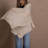 A woman wears a lightweight, fine cashmere wrap shawl in beige
