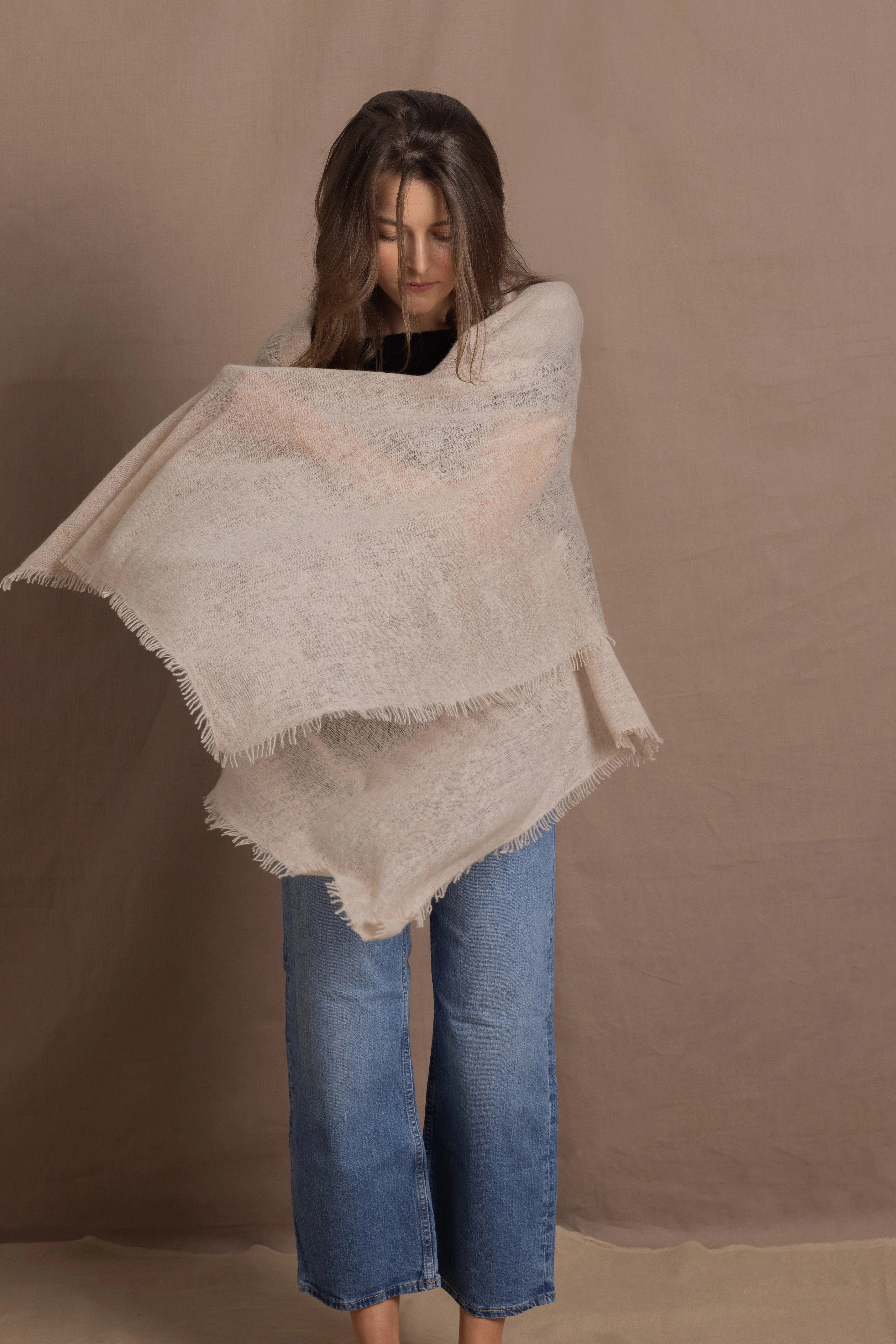 A woman wears a lightweight, fine cashmere wrap shawl in beige