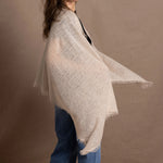 A woman wears a lightweight, fine cashmere shawl in beige