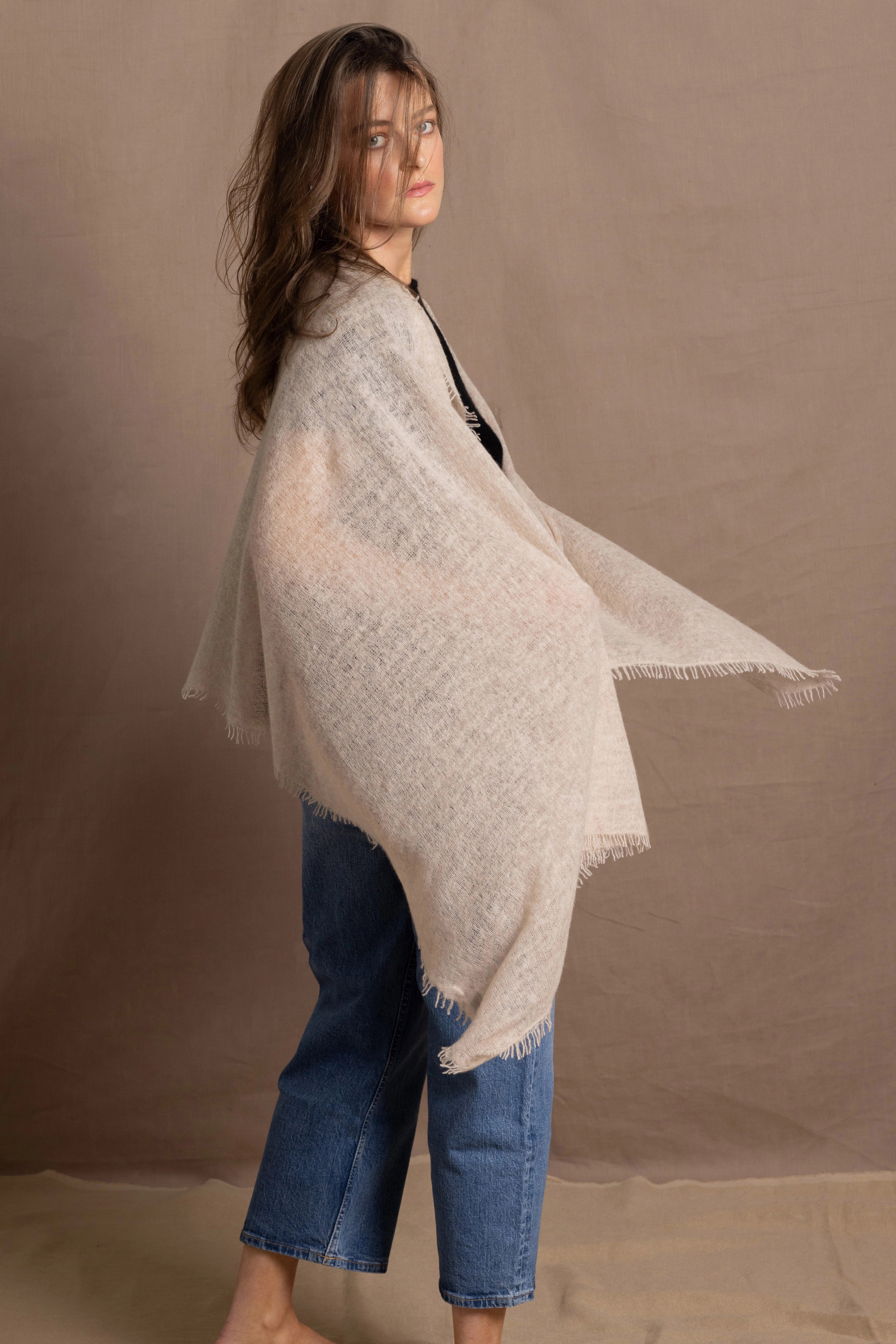 A woman wears a lightweight, fine cashmere shawl in beige
