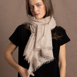 A woman wears a lightweight, fine cashmere wrap scarf tied around her neck with a black cashmere t-shirt underneath