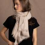 A woman wears a lightweight, fine cashmere wrap scarf tied around her neck with a black cashmere t-shirt underneath
