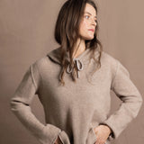 a woman wears a luxury cashmere hoodie in beige with jeans