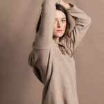 a woman wears a pure, 100% cashmere sweater in beige with jeans