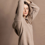 a woman wears a pure, 100% cashmere sweater in beige with jeans