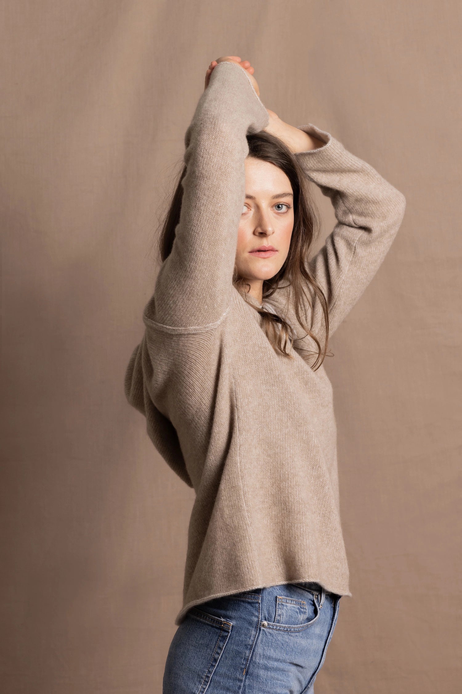 a woman wears a pure, 100% cashmere sweater in beige with jeans