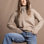a woman wears a pure, 100% cashmere jumper in beige with jeans