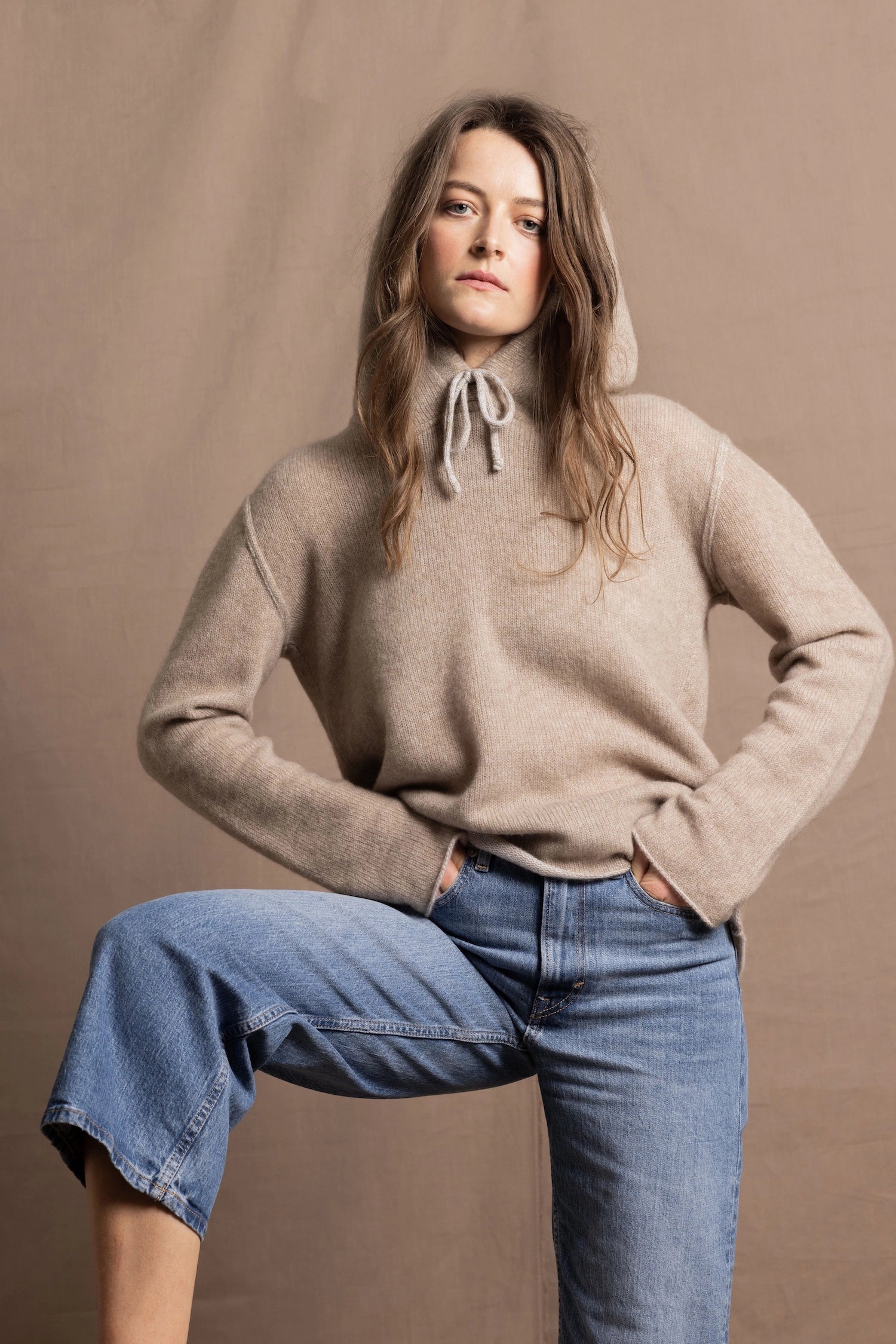 a woman wears a pure, 100% cashmere jumper in beige with jeans