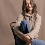 a woman wears a pure, 100% cashmere sweater in beige with jeans