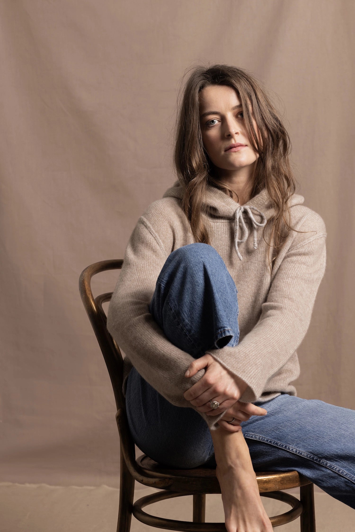 a woman wears a pure, 100% cashmere sweater in beige with jeans