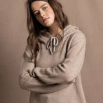 a woman wears a luxury cashmere hoodie sweater in beige with jeans