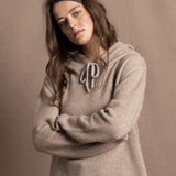 a woman wears a luxury cashmere hoodie sweater in beige with jeans