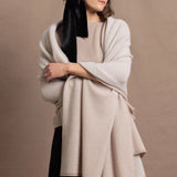 A woman wears a large cashmere shawl in beige over a matching cashmere tee