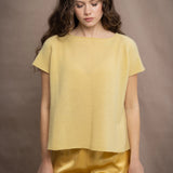 a woman wears a pure 100% cashmere tee sweater in butter yellow over silk trousers in butter yellow