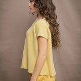a woman wears a pure 100% cashmere tee sweater in butter yellow over silk trousers in butter yellow